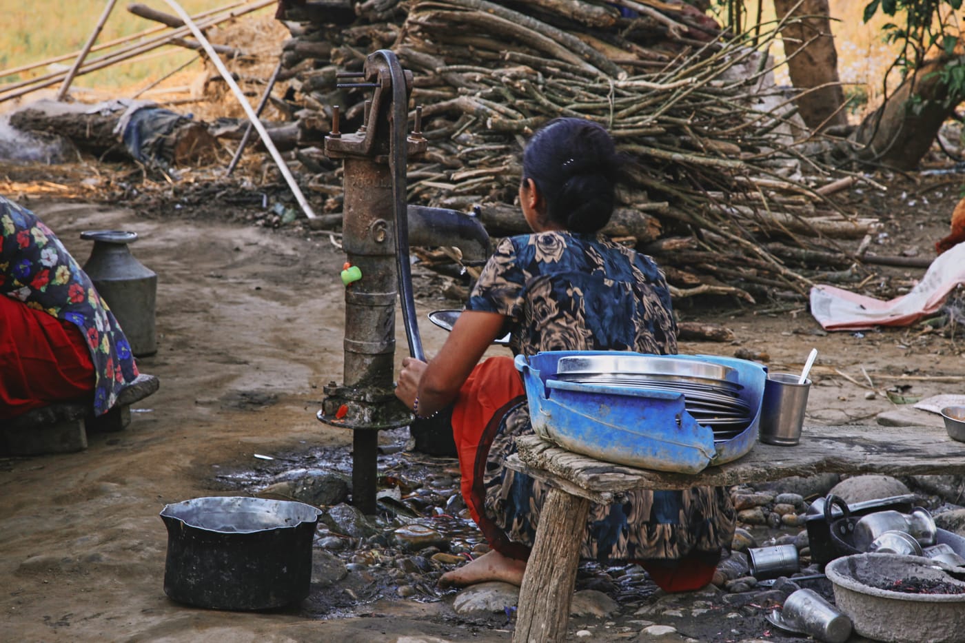 A woman drawing water from a hand pump at a rural humanitarian relief site