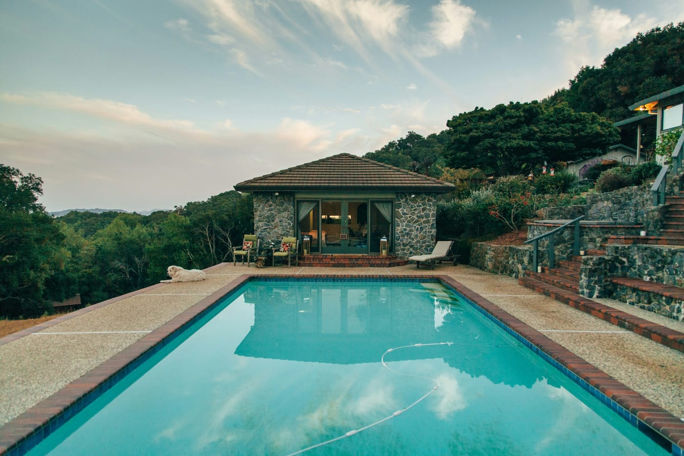 Private villa swimming pool at dusk overlooking wooded hills
